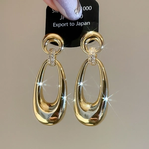 Detailed close-up of gold-plated oval drop earrings with sparkling zircon inlay