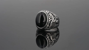 Close-up of vintage steel ring for men with black gemstone and engraved relief details