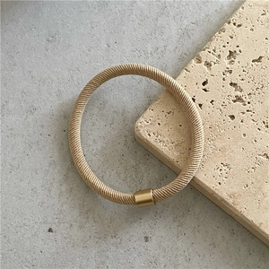Detailed view of khaki twill high-elastic hair tie with decorative gold metal fastener