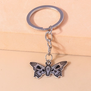 Detail shot of gothic butterfly keychain with skull wings and coffin-shaped body