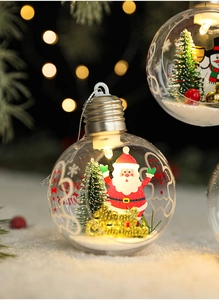 Close-up of a clear Christmas ornament with Santa Claus and warm LED lights