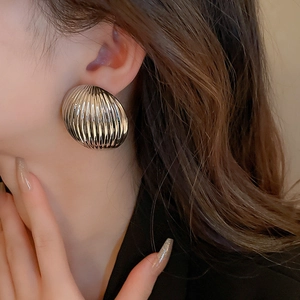 Close-up of silver textured shell-style hoop earrings on a fashion model face