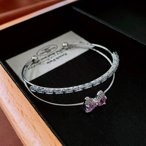 Macro view of double-layer silver bracelet with pink zircon bow and crystals