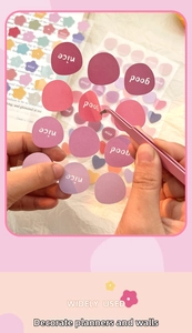 Detail of pink tweezers picking colorful bubble stickers for creative scrapbooking