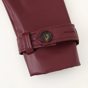 Détail de la manche d'un manteau long en similicuir bordeaux avec bouton en écaille