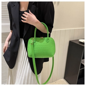 Detail of bright green shell bag with crocodile texture and gold metal hardware