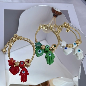 Detail of 18K gold-plated Evil Eye bracelets with colorful enamel charms on mirrors