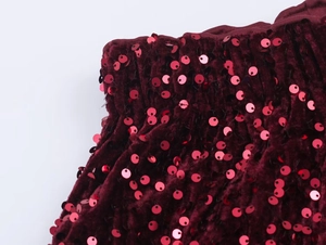 Macro detail of wine red velvet fabric featuring luxury red sequin embellishments and texture