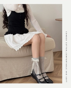 Close-up of gray combed cotton mid-calf socks with white lace bows and ribbons