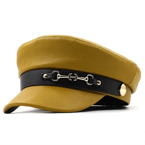 Yellow faux leather newsboy cap with gold horsebit buckle and textured finish
