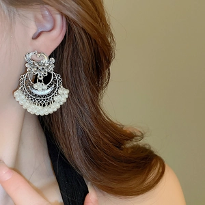 Detailed close-up of retro silver geometric earrings with intricate hollow patterns and pearls