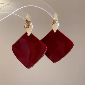 Detail view of large burgundy square drop earrings with geometric gold rhombus stud