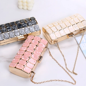 Detail view of acrylic evening clutch with gold chain, marble pattern and metal clasp