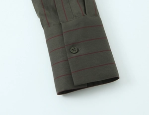 Detail of single-button cuff on olive green striped shirt with fine red horizontal lines