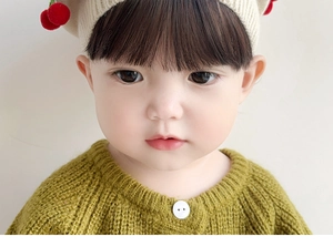 Detailed close-up of mustard green knit cardigan and beige beret with cherry decor