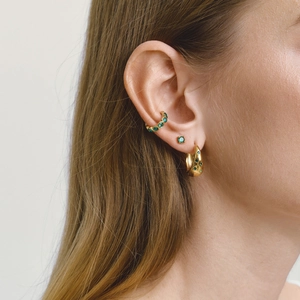 Créoles dorées épaisses et clous d'oreilles avec pierres vertes sur le mannequin