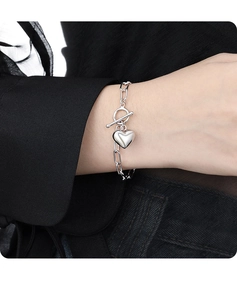 Detail of silver heart charm bracelet with toggle OT clasp on a woman's wrist