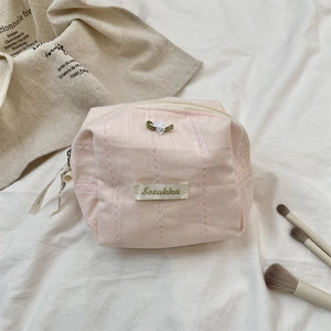 Detailed close-up of a pink textured makeup bag with delicate lace and a white floral accent