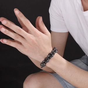 Close-up of vintage silver skull bracelet with oxidized punk finish on male model