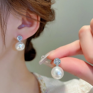 Detail view and model wearing pearl earrings with sparkling crystal accents in silver