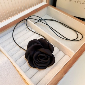 Detail of a black fabric rose pendant necklace placed inside a wooden jewelry gift box
