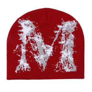 Gros plan du bonnet rouge avec motif jacquard pixelisé de la lettre M blanc et gris