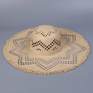 Detailed macro view of hollow-out star pattern on handmade raffia straw sun hat with fringe