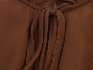 Vue détaillée du décolleté de la robe en mousseline marron foncé avec nœud et coutures