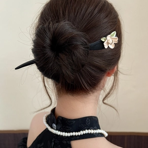 Close-up of elegant hair pin with cream flower and green leaf on professional updo
