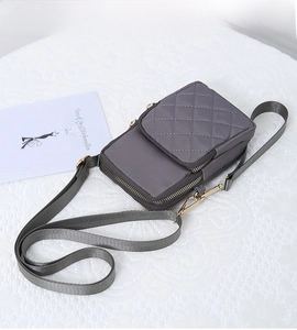 Close-up of dark grey quilted nylon phone bag with gold zippers on white fabric