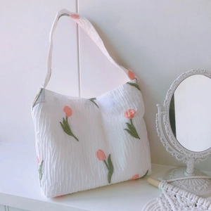 Sac à épaule plissé blanc minimaliste avec broderie de tulipes roses dans un décor intérieur