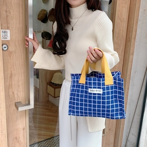 Close-up of blue checkered canvas lunch bag featuring bright yellow ribbon handles