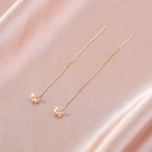 Detail of gold butterfly tassel earrings with sparkling cubic zirconia on silk fabric