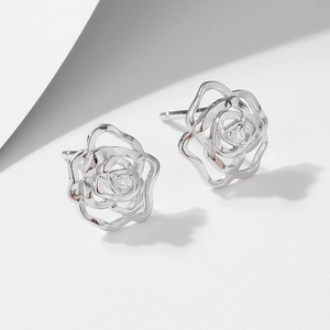 Macro shot of silver rose stud earrings featuring delicate hollow petals and tiny zircon