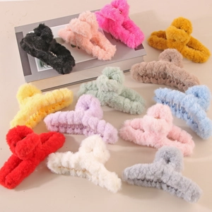 Top view of thirteen colorful plush shark hair clips arranged on a beige background