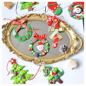 Handmade clay Christmas ornaments featuring wreaths and canes on a golden mirror tray