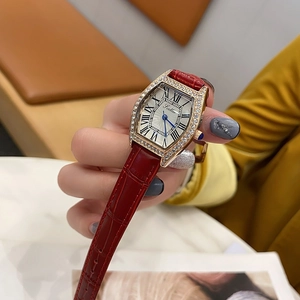 Close-up of luxury tonneau watch with gold diamond bezel and red leather strap