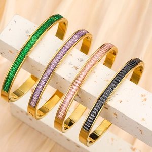 Detail of four gold-plated stainless steel bracelets with baguette-cut colored zircons