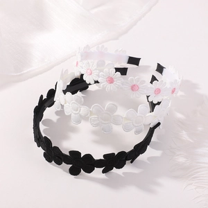 Three stackable daisy embroidery headbands in black and white with detailed floral petals