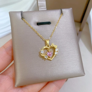 Detail of gold heart pendant with pink gemstone and pavé rhinestones on a fine chain