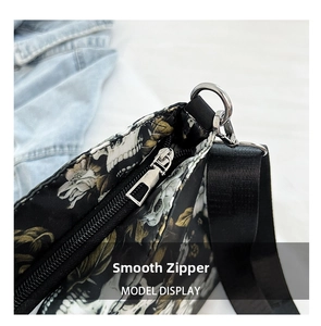 Detail of silver metal zipper and nylon strap on skull floral print crossbody tote bag