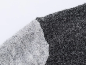 Detailed macro view of color block knit cardigan showing grey wool texture and stitching