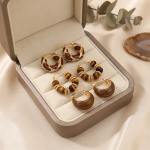 Macro detail of three pairs of vintage tiger eye stone earrings on silk and agate slices