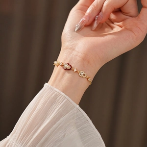 Elegant gold plated bracelet featuring red enamel hearts and pearls on a model wrist