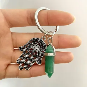 Detail of Hamsa Hand and green hexagonal crystal pillar on a metal keychain