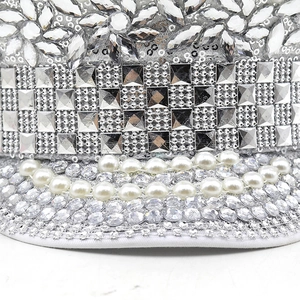 Macro detail of silver sequined military hat with rhinestones, mirror studs and white pearls
