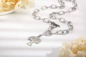 Macro view of silver heart tree pendant and thick metal chain with T-bar toggle clasp