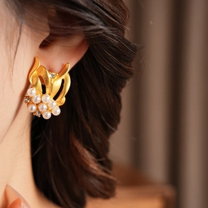 Detail of vintage gold-plated floral earrings with pearls and rhinestones on model