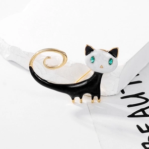 Close-up of enamel cat brooch with emerald green gem eyes and golden spiral tail