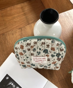 Detailed close-up of quilted floral makeup bag on a wooden table in a lifestyle setting
